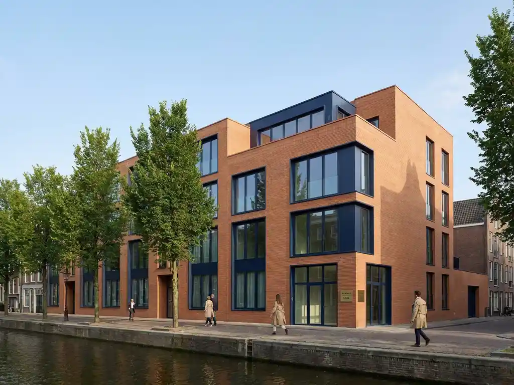 Modern Amsterdam appartementengebouw met glazen ramen en bakstenen gevel langs boomrijke gracht met te koop bord